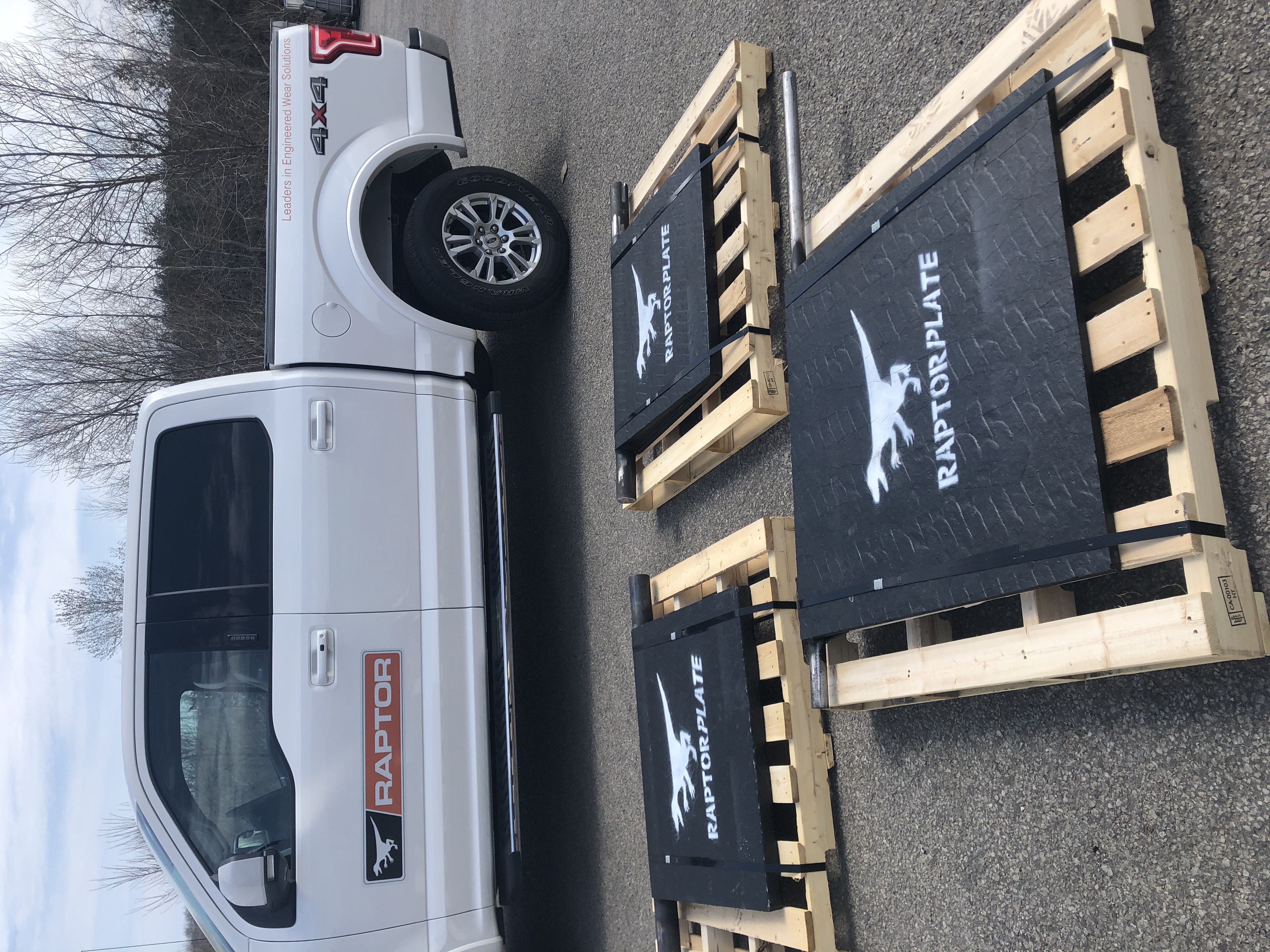 Camioneta Raptor estacionada detr&aacute;s de tres placas de desgaste RaptorPlate sobre paletas de madera