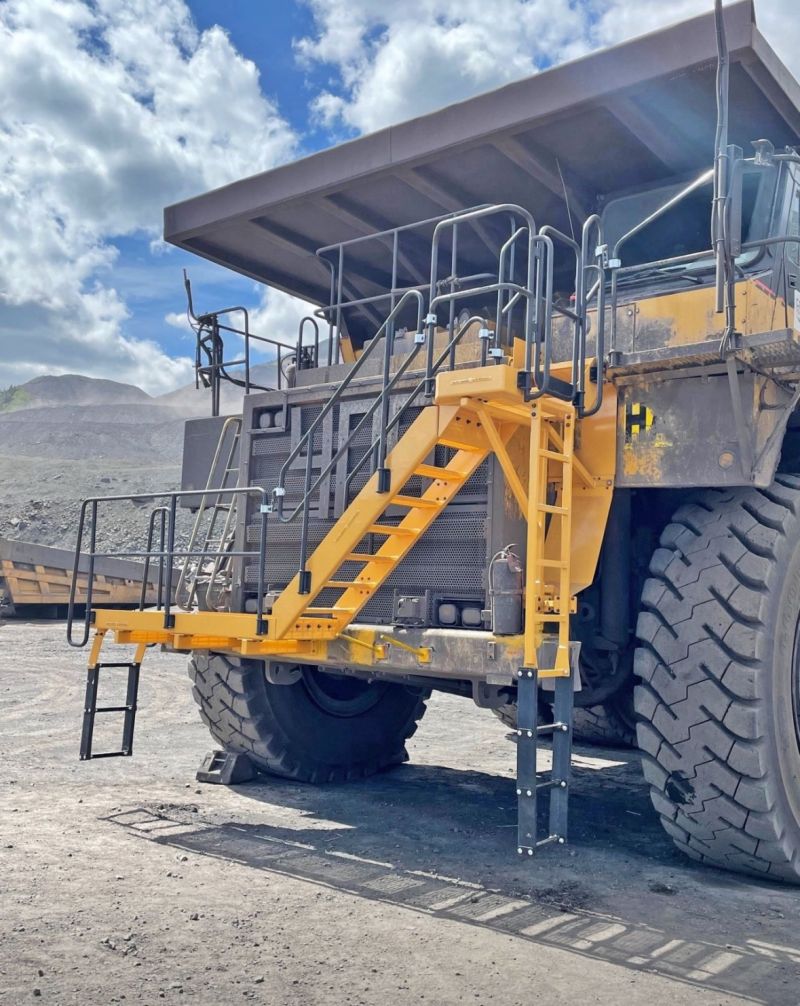 Acceso a un cami&oacute;n de acarreo amarillo con una escalera de abordaje amarilla a&ntilde;adida, escaleras y una plataforma con barandas en una mina